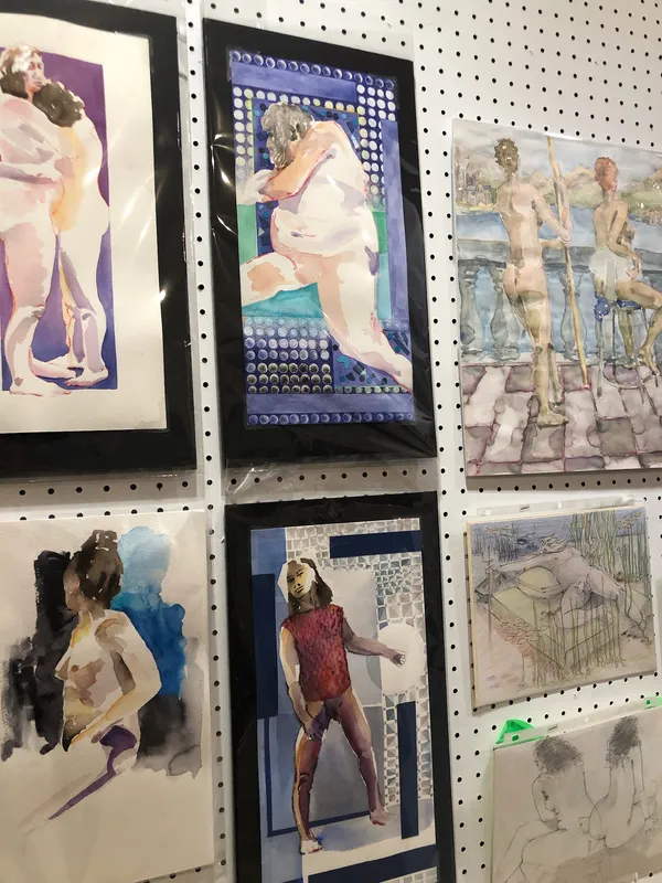 A cluster of colourful watercolour and ink figure studies on a pegboard wall.